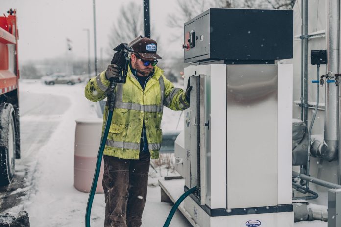 diesel-spill-in-secaucus-creek-raises-questions-ab A man wearing a jacket refuels a truck at a gas station during winter with snow falling.