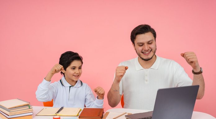 High Tech Senior Named National Merit Semifinalist Father and son joyfully celebrate finishing homework together on a laptop.