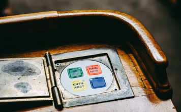 Wooden voting panel with multilingual buttons in Bern's Parliament, Switzerland.