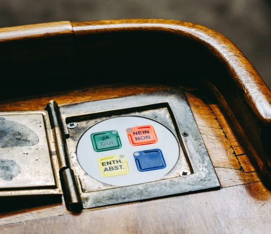 Wooden voting panel with multilingual buttons in Bern's Parliament, Switzerland.