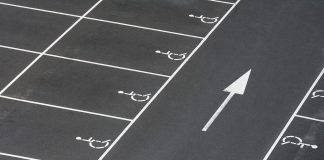 A clean parking lot featuring multiple handicapped spaces and a directional arrow marking.