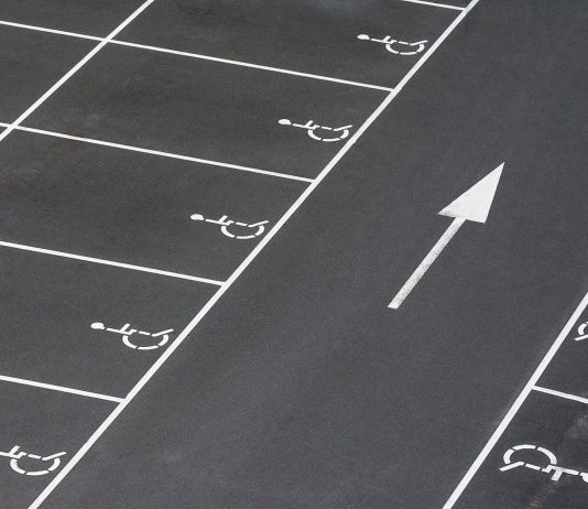 A clean parking lot featuring multiple handicapped spaces and a directional arrow marking.