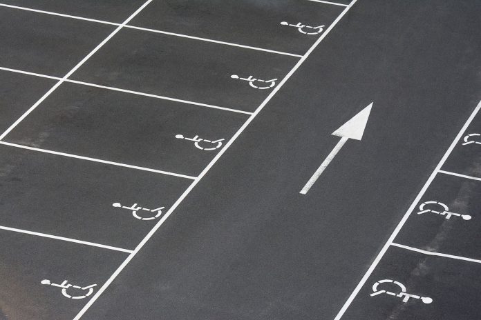 A clean parking lot featuring multiple handicapped spaces and a directional arrow marking.