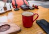 A cozy café setup with a red coffee mug and smartphone on a wooden table.