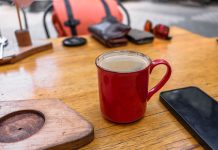 A cozy café setup with a red coffee mug and smartphone on a wooden table.