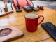 Hoboken’s First Coffee Crawl Brews History and Community A cozy café setup with a red coffee mug and smartphone on a wooden table.