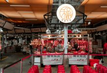 Active Asian market scene showcasing an indoor butcher stall with various meat cuts and vibrant red seating.