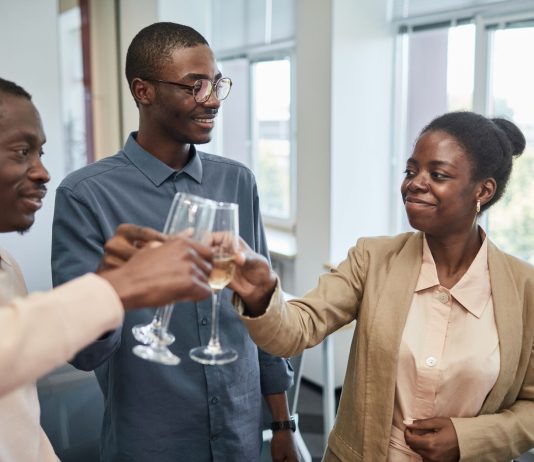 Three adults celebrate with a toast indoors, expressing joy and camaraderie.