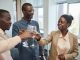 Three adults celebrate with a toast indoors, expressing joy and camaraderie.