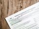 Close-up of a corporate tax form on a textured wooden surface, highlighting document details.