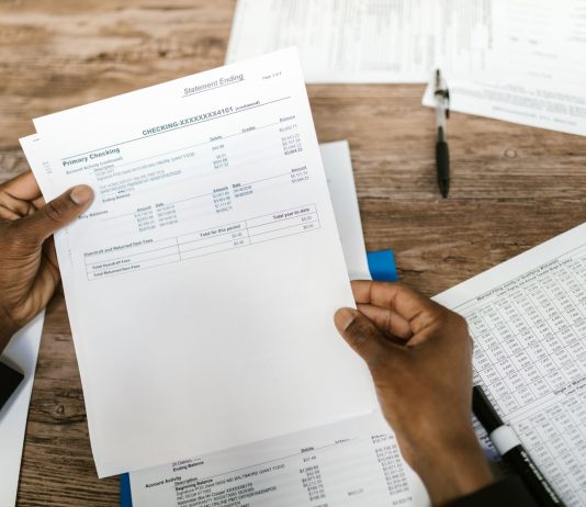 Hands holding financial papers for tax preparation and analysis.
