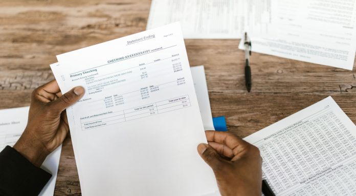 Hands holding financial papers for tax preparation and analysis.