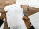 Hands holding financial papers for tax preparation and analysis.
