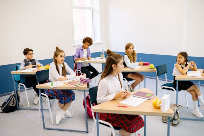 Students learning in a bright, diverse classroom setting, engaged and attentive.