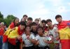 A cheerful group of young people celebrates outdoors, proudly displaying Spanish flags and team jerseys.