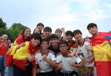 A cheerful group of young people celebrates outdoors, proudly displaying Spanish flags and team jerseys.