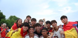 A cheerful group of young people celebrates outdoors, proudly displaying Spanish flags and team jerseys.