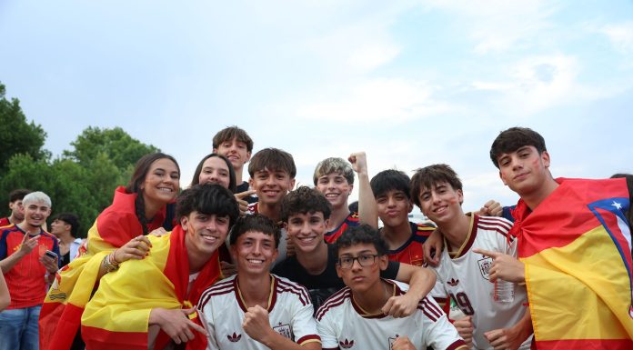 A cheerful group of young people celebrates outdoors, proudly displaying Spanish flags and team jerseys.
