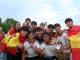 A cheerful group of young people celebrates outdoors, proudly displaying Spanish flags and team jerseys.