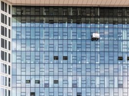 High-rise glass building exterior with window cleaners in Hamburg, Germany.