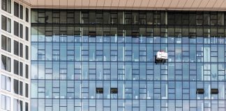 High-rise glass building exterior with window cleaners in Hamburg, Germany.