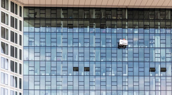 High-rise glass building exterior with window cleaners in Hamburg, Germany.