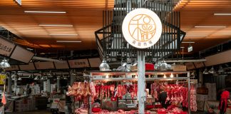 Active Asian market scene showcasing an indoor butcher stall with various meat cuts and vibrant red seating.