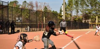 A dynamic moment during a women's softball game with the batter hitting the ball.