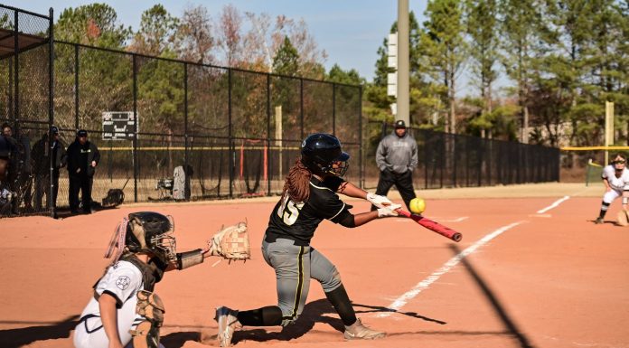A dynamic moment during a women's softball game with the batter hitting the ball.