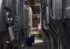 Inside view of a modern brewery with large stainless steel tanks and machinery for beer production.