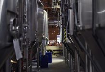 Inside view of a modern brewery with large stainless steel tanks and machinery for beer production.