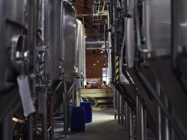 Inside view of a modern brewery with large stainless steel tanks and machinery for beer production.