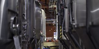 Inside view of a modern brewery with large stainless steel tanks and machinery for beer production.