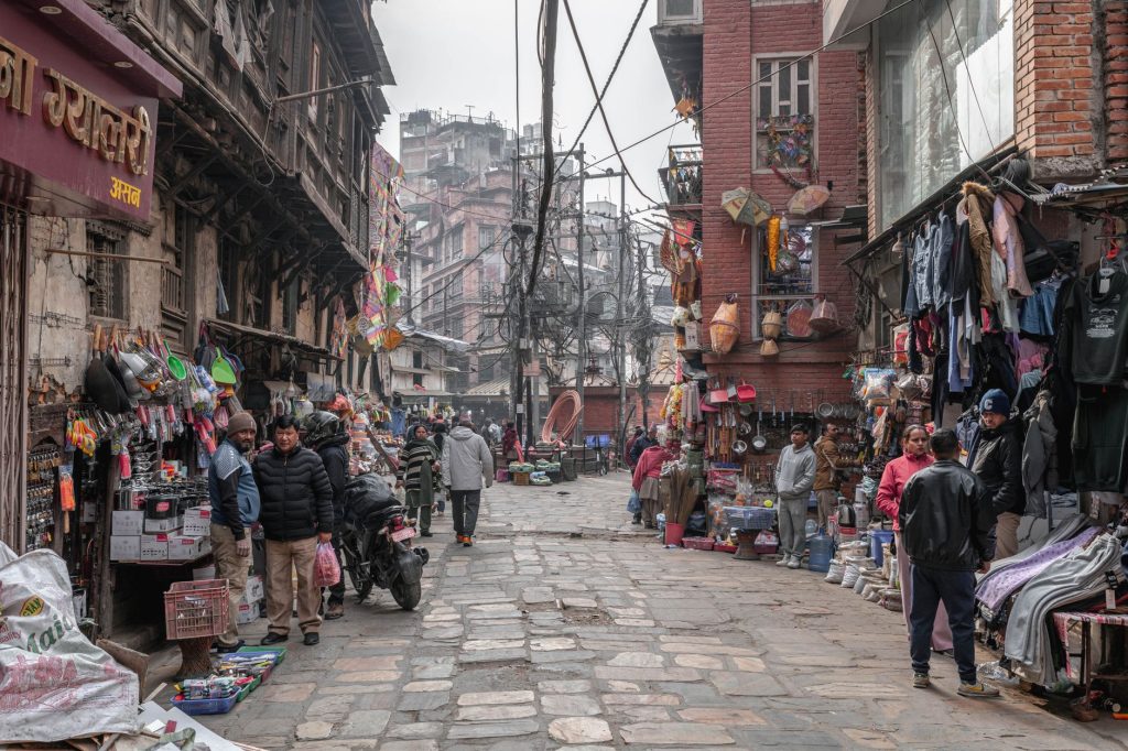 Street view of a lively market in Kathmandu, Nepal with vendors and shoppers.