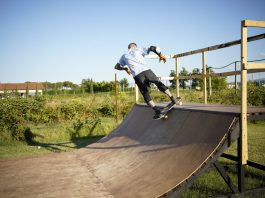 ÚLTIMA HORA: Shred.Co, programa de skate adaptado cerca de Hoboken Skateboarder executing a trick on a wooden outdoor skate ramp with lush greenery in the background.