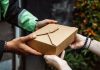 Close-up of a delivery person handing over a box to a customer outdoors.