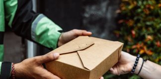 Close-up of a delivery person handing over a box to a customer outdoors.