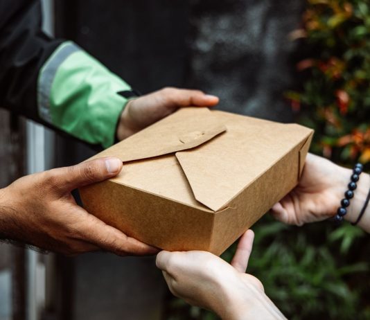 ÚLTIMA HORA: Taller gratuito de DoorDash para negocios locales en Hudson Close-up of a delivery person handing over a box to a customer outdoors.