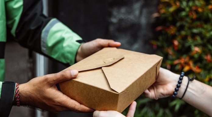 Close-up of a delivery person handing over a box to a customer outdoors.