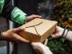 Close-up of a delivery person handing over a box to a customer outdoors.