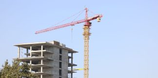 Concrete high-rise building under construction with a tower crane in Uzbekistan.