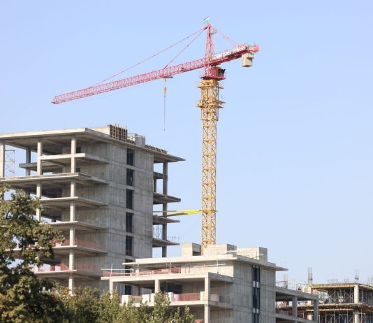 Concrete high-rise building under construction with a tower crane in Uzbekistan.
