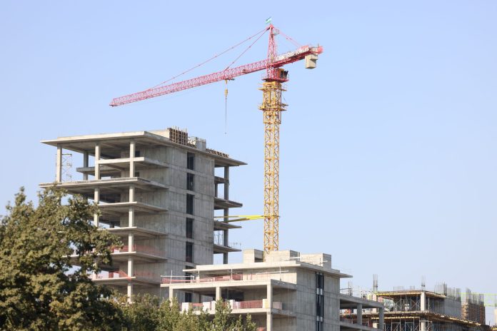Concrete high-rise building under construction with a tower crane in Uzbekistan.