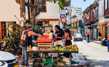 Mejor Comida Colombiana en North Bergen: 7 Lugares Para Probar (Guía 2026) Vibrant street market scene with a fruit vendor in Cartagena, Colombia's historic district.