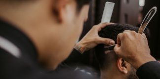 Las Mejores Barberías y Salones en Union City, NJ (2026): Guía Local Completa Close-up of a barber expertly styling a man's hair with a razor and comb in a trendy barbershop.