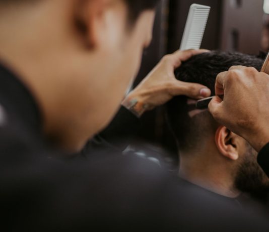 Las Mejores Barberías y Salones en Union City, NJ (2026): Guía Local Completa Close-up of a barber expertly styling a man's hair with a razor and comb in a trendy barbershop.
