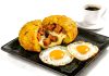Delicious Ecuadorian breakfast featuring mote pillo, fried eggs, and coffee on a black plate.
