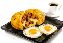 Delicious Ecuadorian breakfast featuring mote pillo, fried eggs, and coffee on a black plate.