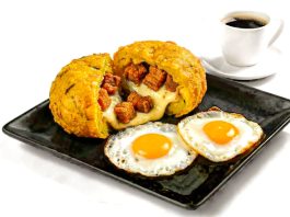 Delicious Ecuadorian breakfast featuring mote pillo, fried eggs, and coffee on a black plate.