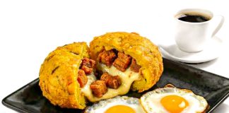 Delicious Ecuadorian breakfast featuring mote pillo, fried eggs, and coffee on a black plate.